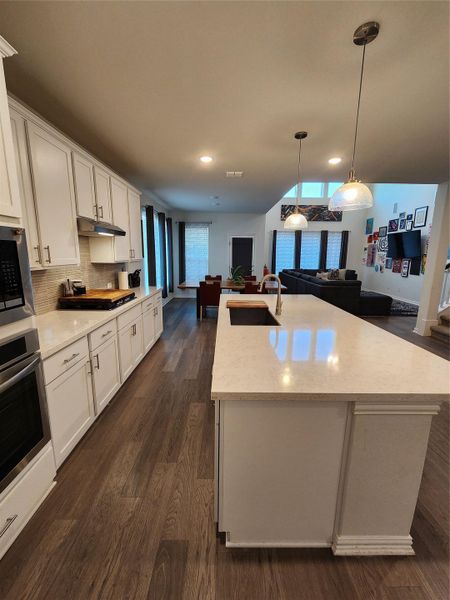 An open-concept living space with a pristine kitchen island and rich wood flooring.