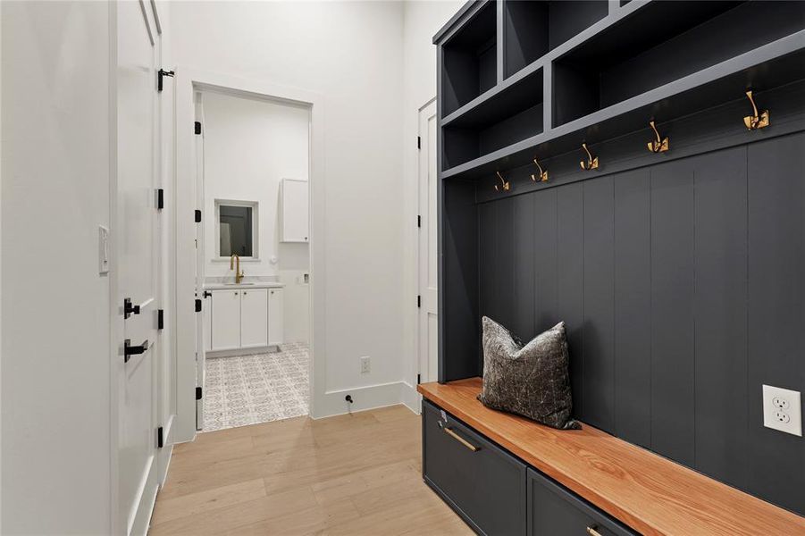 Mudroom featuring light wood finished floors and a sink