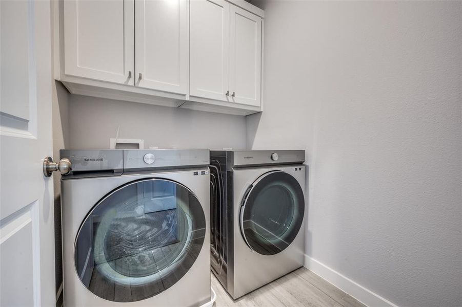 Laundry room featuring baseboards, cabinet space, independent washer and dryer, and light wood finished floors