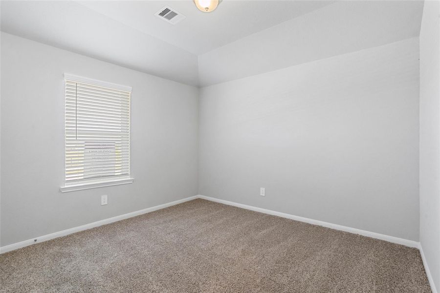 This cozy secondary bedroom offers plush soft carpeting, neutral walls ready for personalization, a sun-filled window with fitted blinds, sloped ceilings, and a spacious closet for all your storage needs.