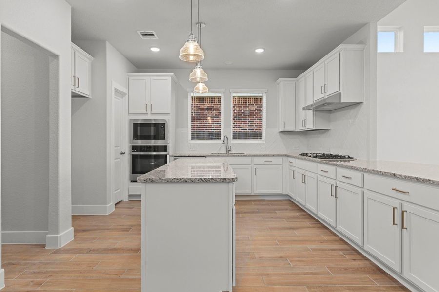The gourmet kitchen is a showpiece of style and function! Bright white shaker cabinets, sparkling granite countertops, pendant lighting, and a gas cooktop make this space perfect for both everyday meals and entertaining in style.