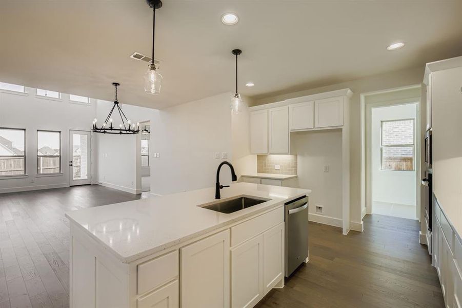 Kitchen featuring healthy amount of natural light, white cabinetry, dark wood-style floors, decorative light fixtures, and recessed lighting Kitchen featuring healthy amount of natural light, white cabinetry, dark wood-style floors, decorative light fixtures, and recessed lighting