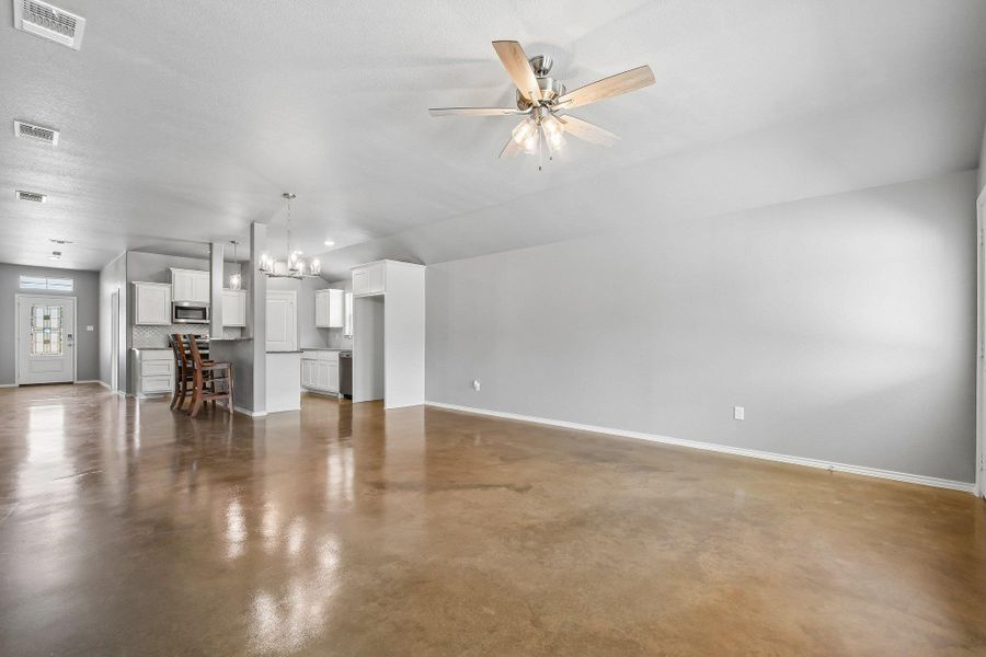 An open concept living area features resilient polished concrete floors and a modern ceiling fan for comfortable living. An open concept living area features resilient polished concrete floors and a modern ceiling fan for comfortable living.
