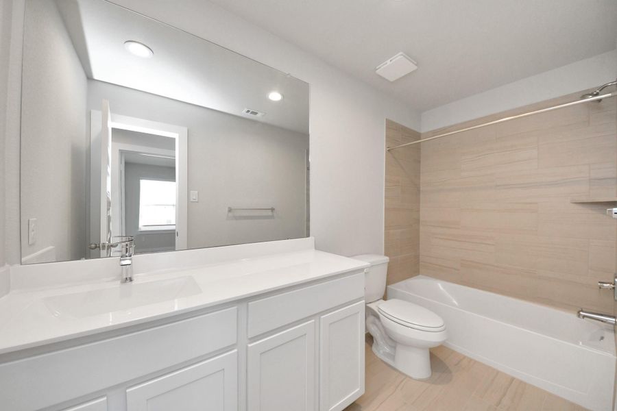 Secondary bath features tile flooring, bath/shower combo with tile surround, light stained wood cabinets, beautiful light countertop. Sample photo of completed home with similar floor plan. Actual colors and selections may vary. Secondary bath features tile flooring, bath/shower combo with tile surround, light stained wood cabinets, beautiful light countertop. Sample photo of completed home with similar floor plan. Actual colors and selections may vary.