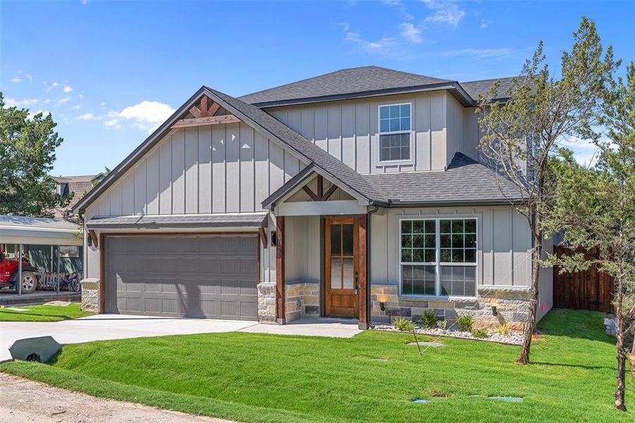 View of front facade featuring a garage and a front lawn