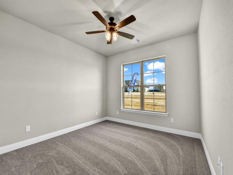 Carpeted spare room featuring ceiling fan