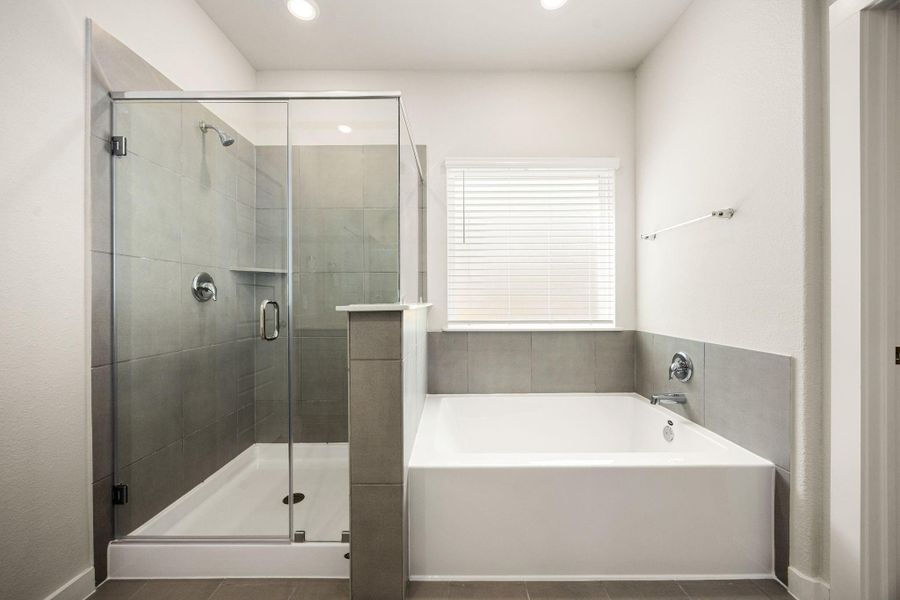This additional view of the primary bath highlights a walk-in shower with elegant tile surround, a separate garden tub ideal for relaxing after a long day, and a large window with privacy blinds that offers both natural light and privacy. This additional view of the primary bath highlights a walk-in shower with elegant tile surround, a separate garden tub ideal for relaxing after a long day, and a large window with privacy blinds that offers both natural light and privacy.