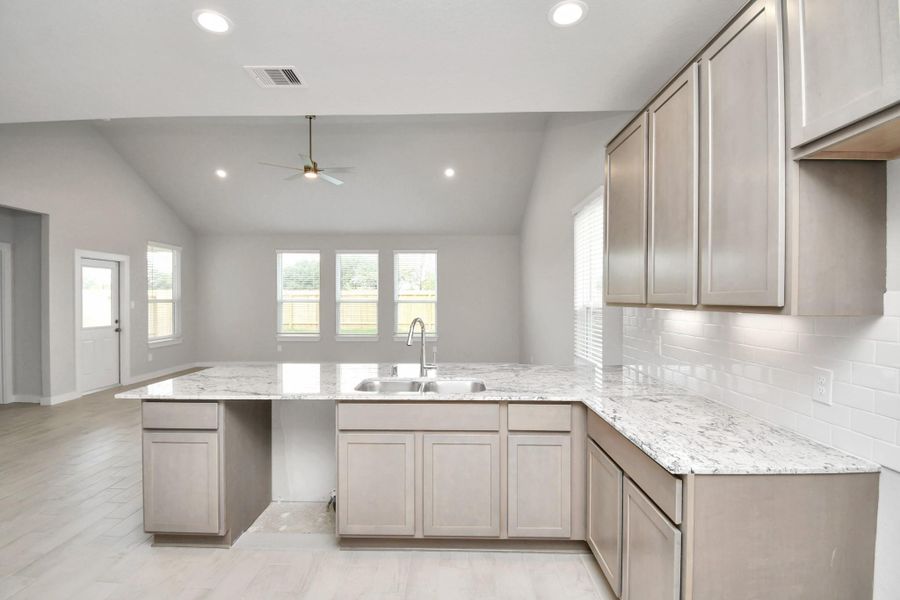 The kitchen is a culinary haven, featuring granite countertops, a tile backsplash, stainless steel appliances, 42” upper cabinets, and undercabinet lighting.