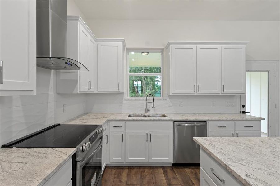 Contemporary kitchen featuring white shaker cabinetry, stainless steel appliances, light-toned countertops, a full subway tile backsplash, and wood-finish flooring Contemporary kitchen featuring white shaker cabinetry, stainless steel appliances, light-toned countertops, a full subway tile backsplash, and wood-finish flooring