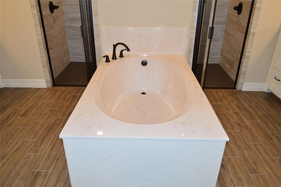 Bathroom with wood tiled floors, a shower stall, and a garden tub