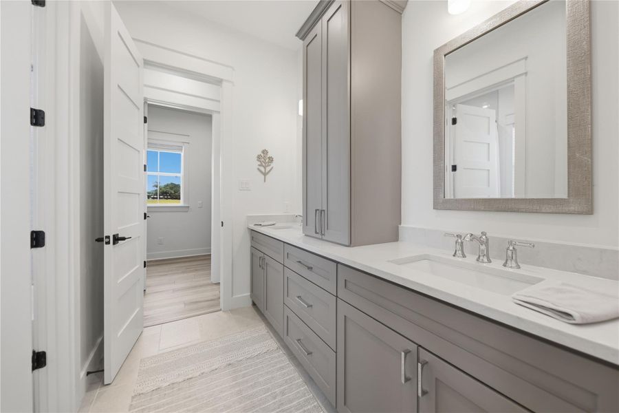 Dual vanities with sleek white counters offer ample space in this well-lit primary bathroom.
