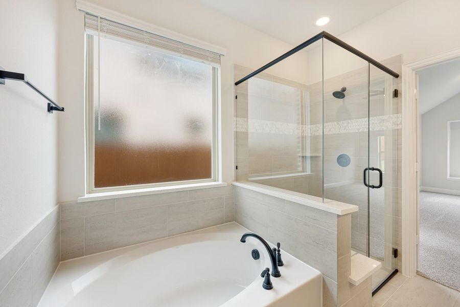 Bathroom with soaking tub, glass-enclosed shower, gray tile walls, and black fixtures Bathroom with soaking tub, glass-enclosed shower, gray tile walls, and black fixtures