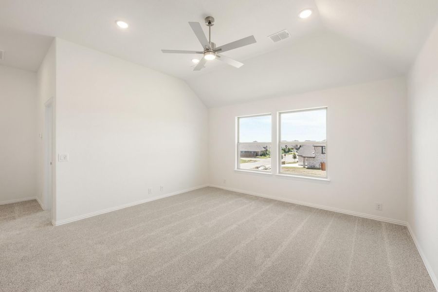 Empty bedroom with vaulted ceiling, ceiling fan, carpet flooring, and double windows overlooking neighborhood Empty bedroom with vaulted ceiling, ceiling fan, carpet flooring, and double windows overlooking neighborhood