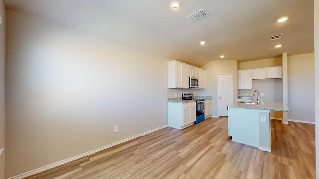 Kitchen with stainless steel appliances, white cabinetry, recessed lighting, light wood-type flooring, and a center island with sink