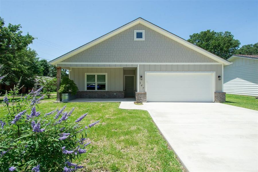 View of front of property featuring a front yard, an attached garage, brick & siding, and driveway View of front of property featuring a front yard, an attached garage, brick & siding, and driveway