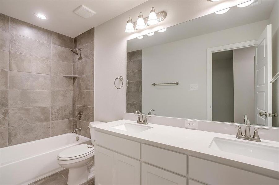 Full bathroom featuring shower combination, double vanity, recessed lighting, and tile patterned floors Full bathroom featuring shower combination, double vanity, recessed lighting, and tile patterned floors