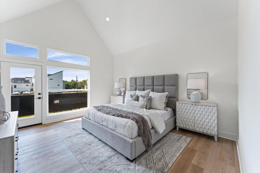 Spacious primary bedroom with 20 ft cathedral ceilings and balcony.