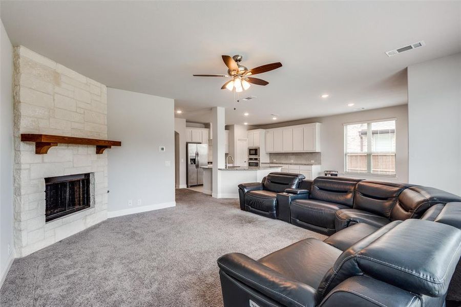 Living room featuring ceiling fan, light colored carpet, and a fireplace