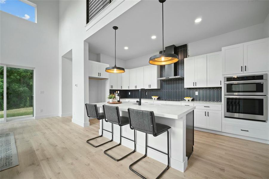 Kitchen featuring stainless steel double oven, light countertops, a high ceiling, tasteful backsplash, and healthy amount of natural light Kitchen featuring stainless steel double oven, light countertops, a high ceiling, tasteful backsplash, and healthy amount of natural light