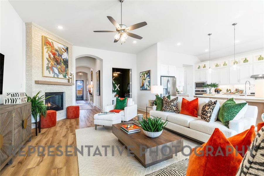 Living room with a fireplace, light wood-style floors, arched walkways, a ceiling fan, and recessed lighting Living room with a fireplace, light wood-style floors, arched walkways, a ceiling fan, and recessed lighting