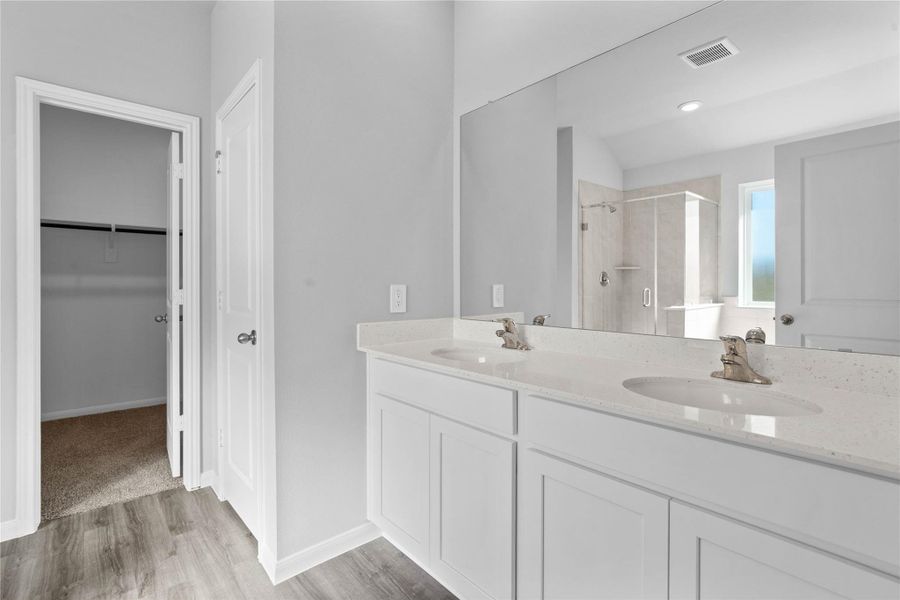 A bright and functional primary bath offering dual sinks for busy mornings, a large mirror, soaking tub, and a modern glass-enclosed shower, creating a serene and efficient space. A bright and functional primary bath offering dual sinks for busy mornings, a large mirror, soaking tub, and a modern glass-enclosed shower, creating a serene and efficient space.