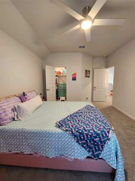 A comfortable bedroom features plush carpeting and a modern ceiling fan for ultimate comfort.