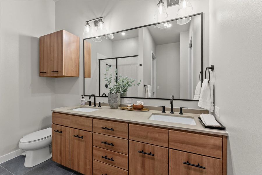 Full bath with double vanity, a stall shower, and tile patterned flooring