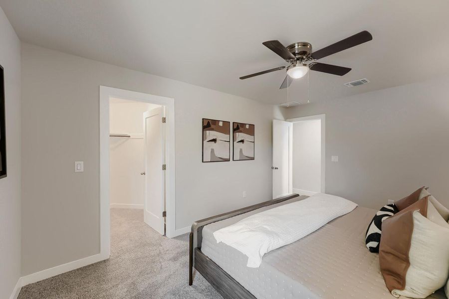 A tranquil sleeping space featuring soft gray carpet and a modern ceiling fan. A tranquil sleeping space featuring soft gray carpet and a modern ceiling fan.