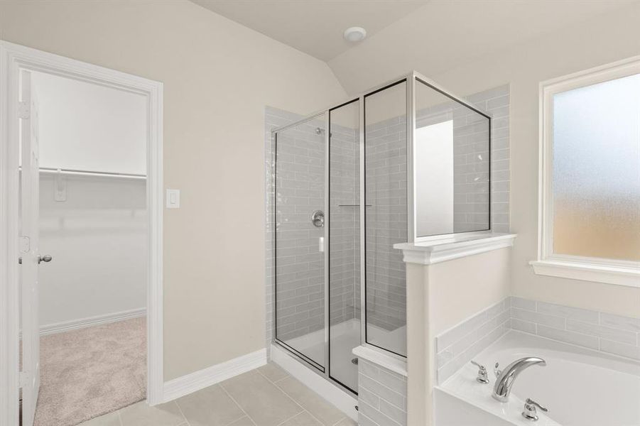 This additional view of your primary bathroom features tile flooring, fresh paint, walk-in shower, a separate garden tub, and a large walk-in closet.