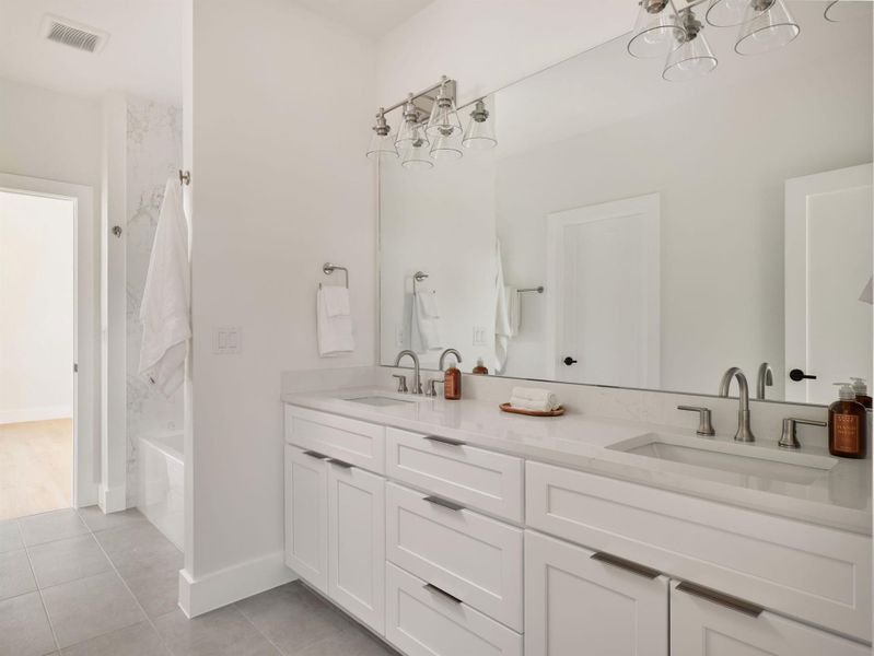 Bathroom featuring double vanity, light tile patterned floors, a chandelier, and bathtub / shower combination Bathroom featuring double vanity, light tile patterned floors, a chandelier, and bathtub / shower combination