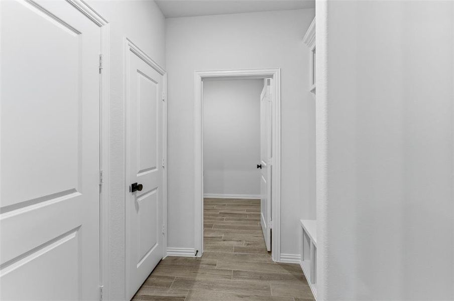 Interior hallway featuring plank-style flooring, white walls, and white trim