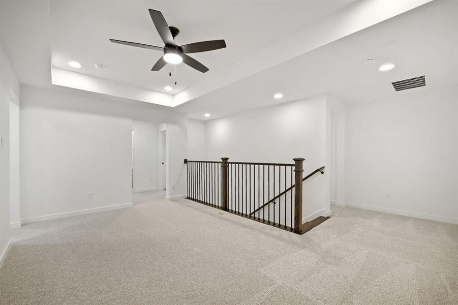 Carpeted upper-level space featuring a tray ceiling with recessed lighting and a ceiling fan Carpeted upper-level space featuring a tray ceiling with recessed lighting and a ceiling fan