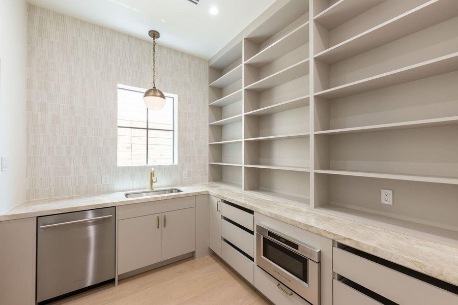 A designer’s answer to everyday function, this thoughtfully appointed back kitchen pairs textured tile with warm custom cabinetry and expansive open storage. From morning espresso rituals to holiday meal prep, every tool and ingredient has its place—keeping the main living areas effortlessly pristine.