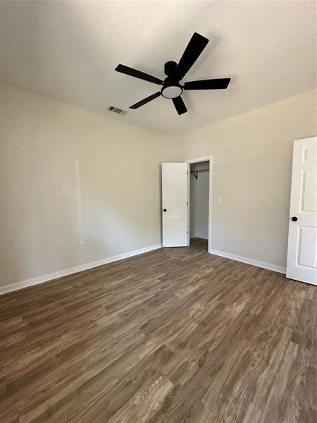 Unfurnished bedroom with dark wood-type flooring, a ceiling fan, and a textured ceiling