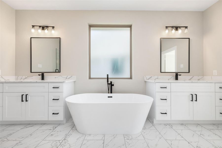 The dual sinks, each with ample storage, provide plenty of space for daily routines. Elegant marble-like flooring complements the neutral color palette, while abundant natural light fills the room, creating a bright and inviting atmosphere perfect for relaxation and self-care.