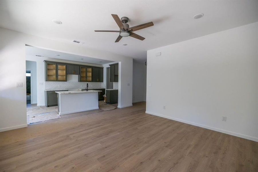 Unfurnished living room featuring light hardwood / wood-style floors, sink, and ceiling fan