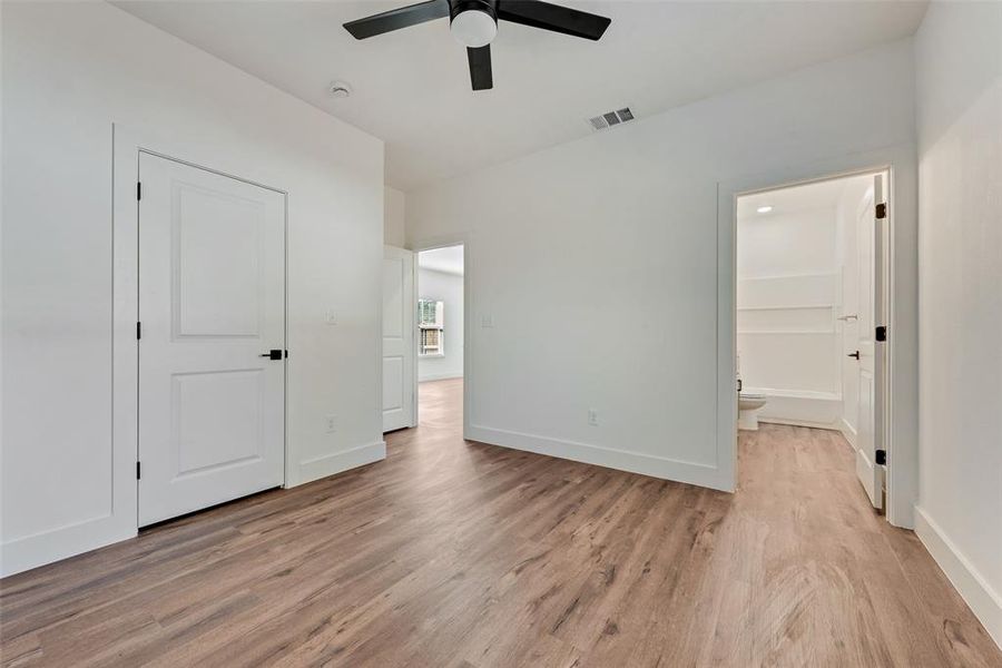 Unfurnished bedroom featuring light wood-style flooring, ceiling fan, and connected bathroom Unfurnished bedroom featuring light wood-style flooring, ceiling fan, and connected bathroom