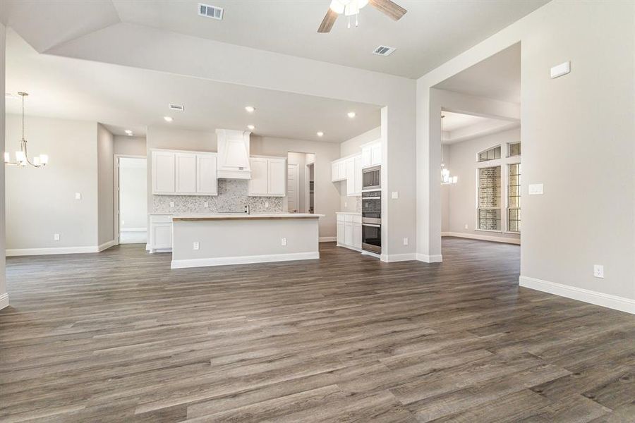 Unfurnished living room featuring a chandelier, dark wood finished floors, recessed lighting, and a ceiling fan Unfurnished living room featuring a chandelier, dark wood finished floors, recessed lighting, and a ceiling fan