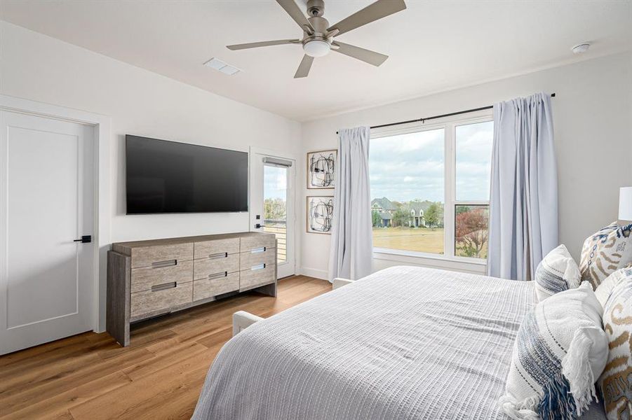 Bedroom with light wood-style flooring, multiple windows, ceiling fan, and access to exterior