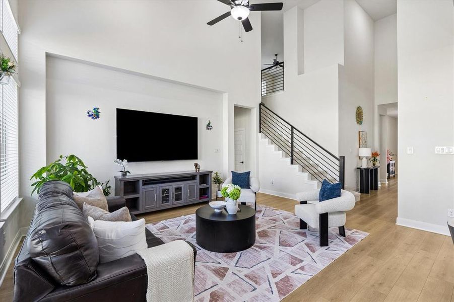 Living area featuring high ceilings, wood-finish flooring, and a contemporary ceiling fan Living area featuring high ceilings, wood-finish flooring, and a contemporary ceiling fan