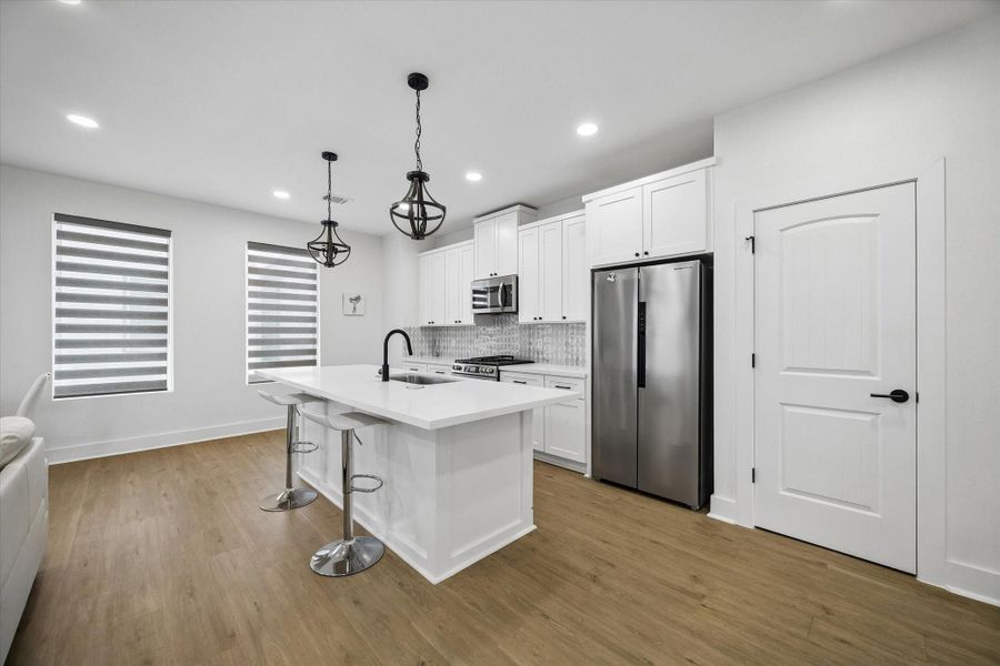 White shaker cabinets and black lantern pendants anchor the kitchen. Counter seating at the island keeps company close while you cook. White shaker cabinets and black lantern pendants anchor the kitchen. Counter seating at the island keeps company close while you cook.
