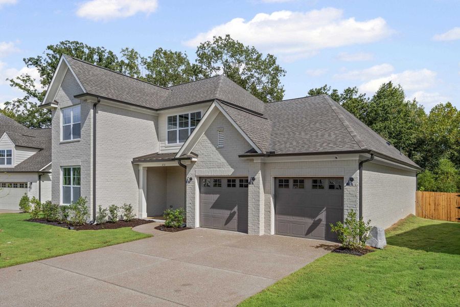 View of front of home featuring brick siding, roof with shingles, driveway, and an attached garage