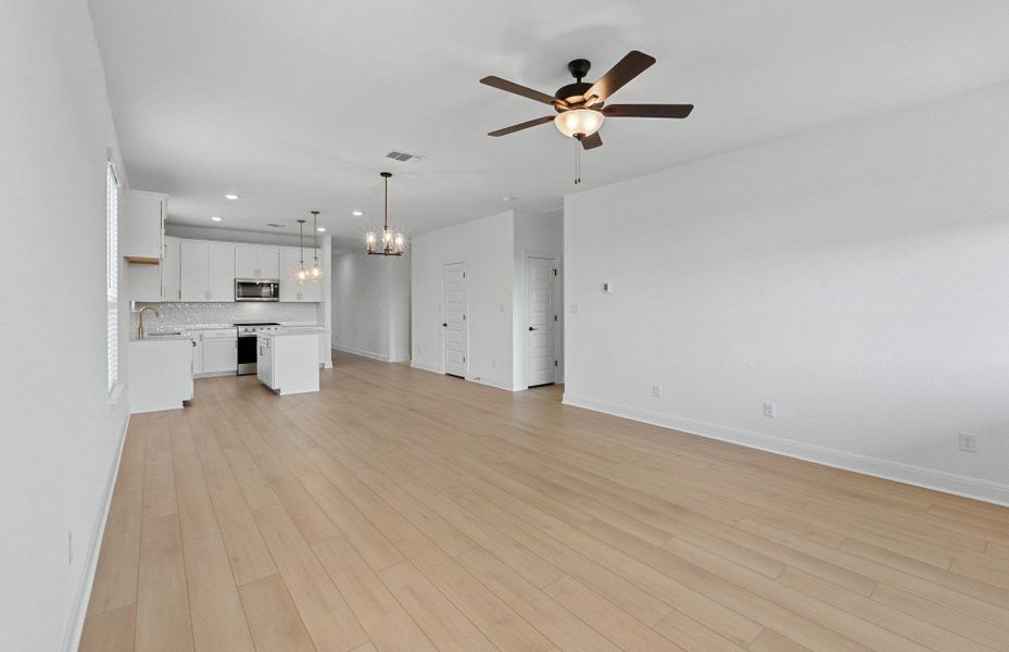 Unfurnished living room featuring a chandelier, light wood-type flooring, recessed lighting, and a ceiling fan Unfurnished living room featuring a chandelier, light wood-type flooring, recessed lighting, and a ceiling fan