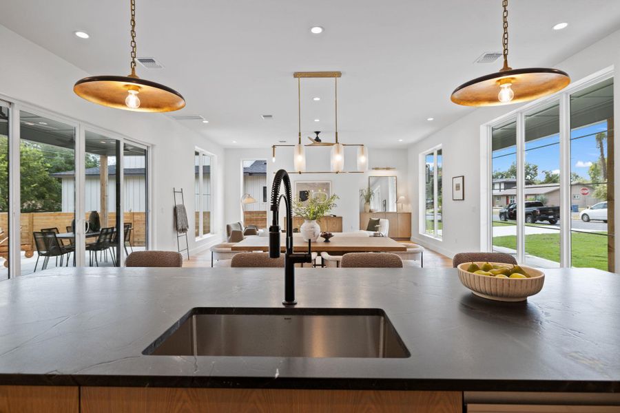 Kitchen featuring an island with sink, recessed lighting, decorative light fixtures, open floor plan, and dark stone counters Kitchen featuring an island with sink, recessed lighting, decorative light fixtures, open floor plan, and dark stone counters