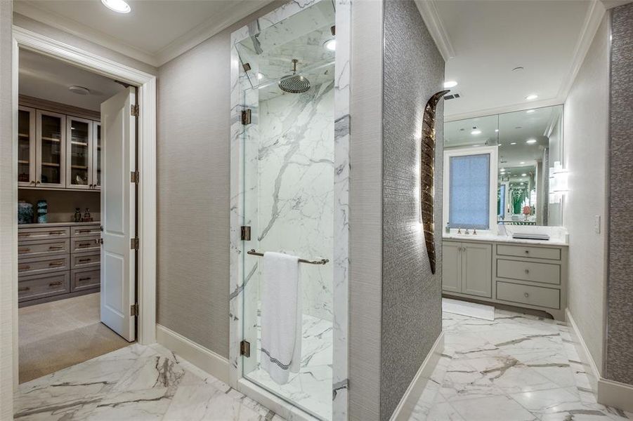 Primary bath featuring Waterworks fittings and slab marble shower, dual water closets, vintage sconce positioned on the shimmering wall covering