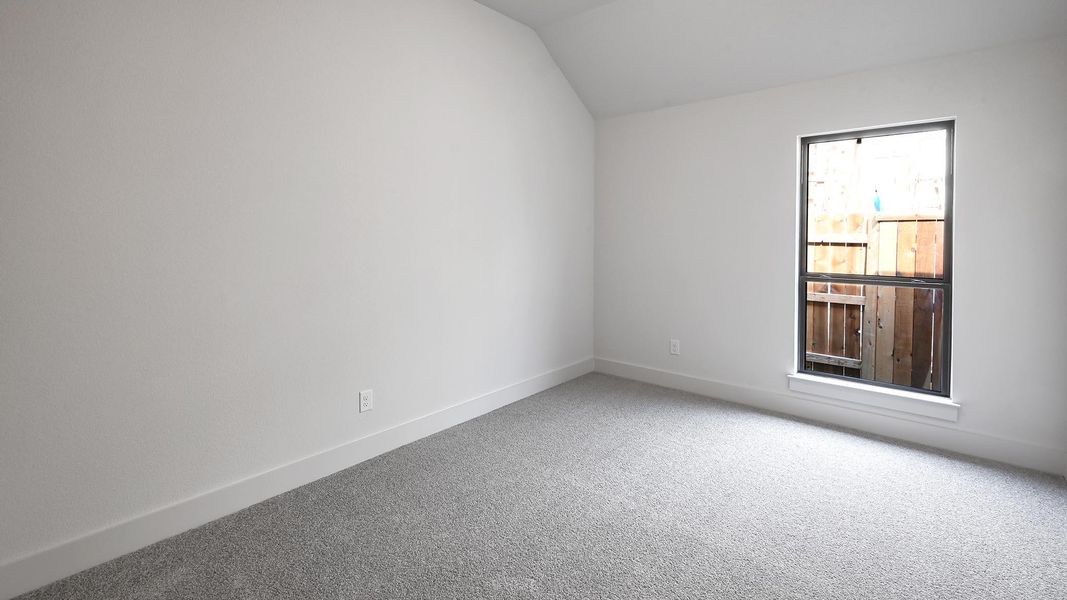 Carpeted empty room with vaulted ceiling and baseboards