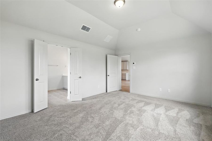 Unfurnished bedroom with light colored carpet and vaulted ceiling Unfurnished bedroom with light colored carpet and vaulted ceiling