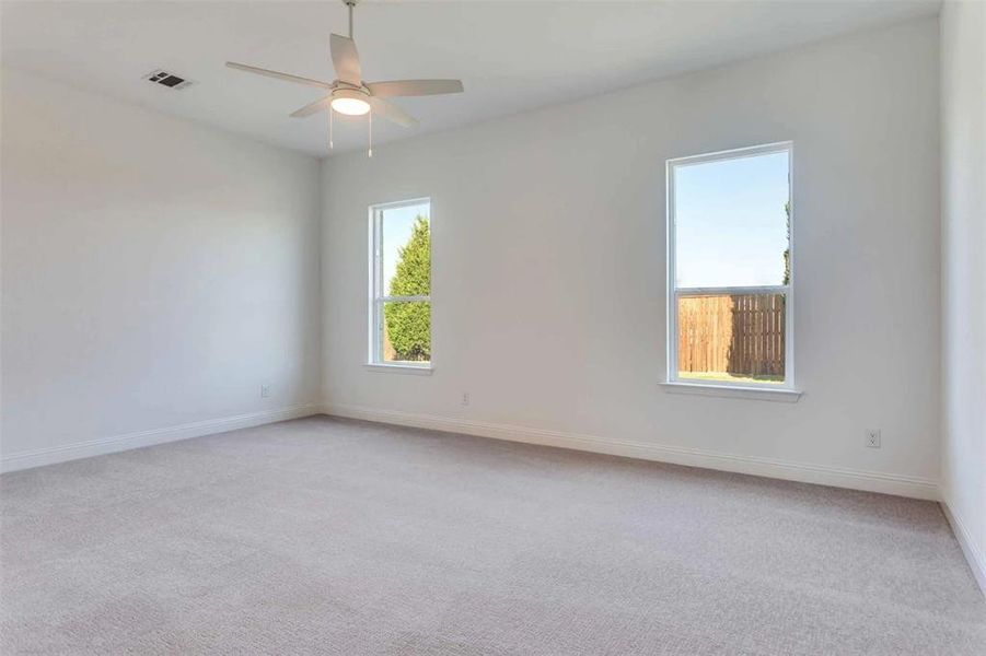 Empty room with light carpet and a ceiling fan Empty room with light carpet and a ceiling fan