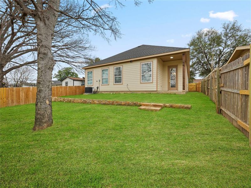 Rear view of house featuring a fenced backyard and roof with shingles