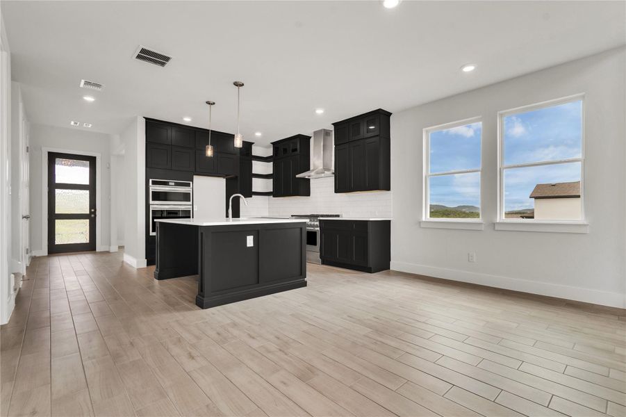 An open-concept living space highlights a modern kitchen with sleek black cabinetry and a bright, airy atmosphere.
